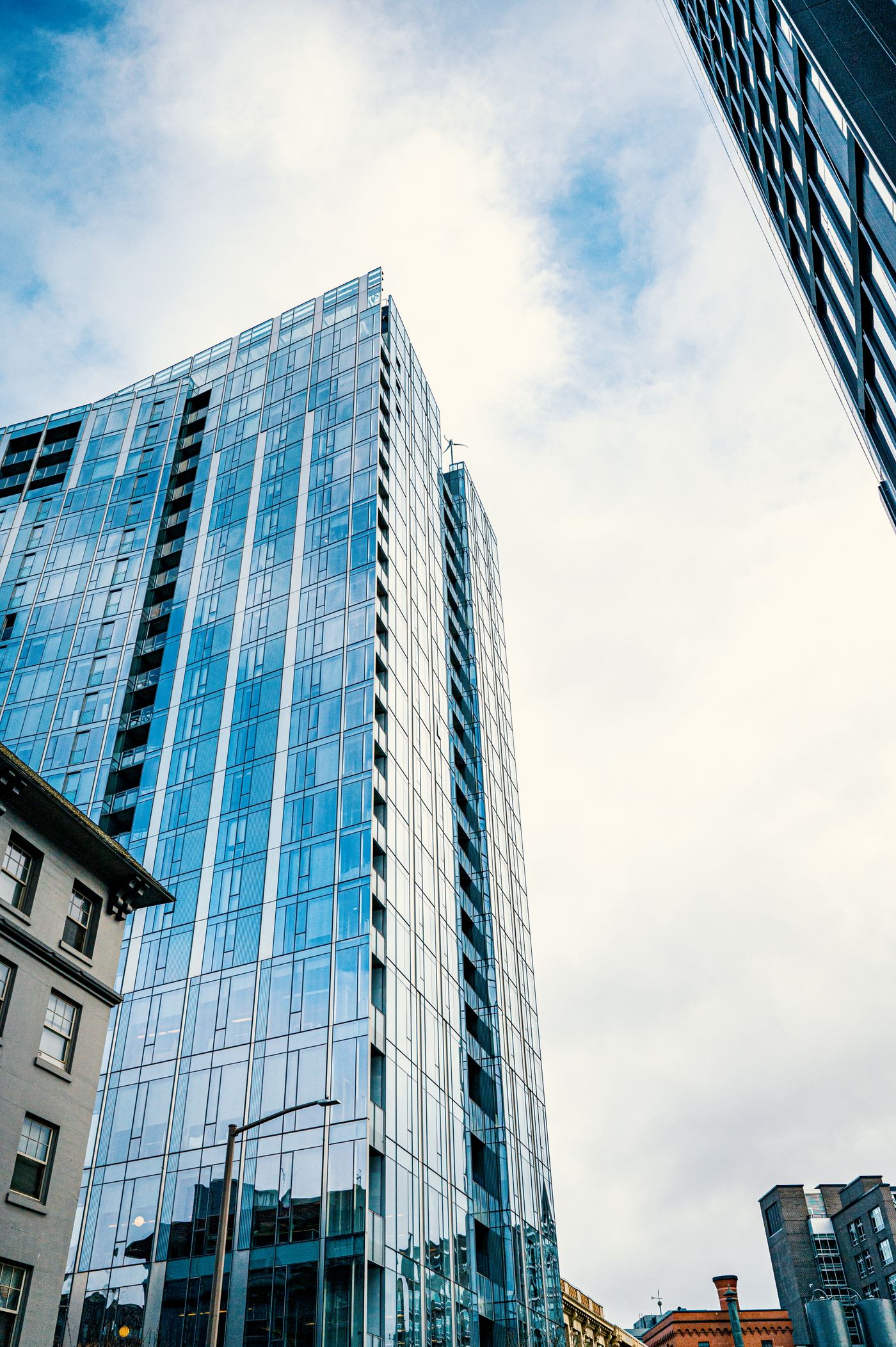 A glass-clad residential tower seen from street level